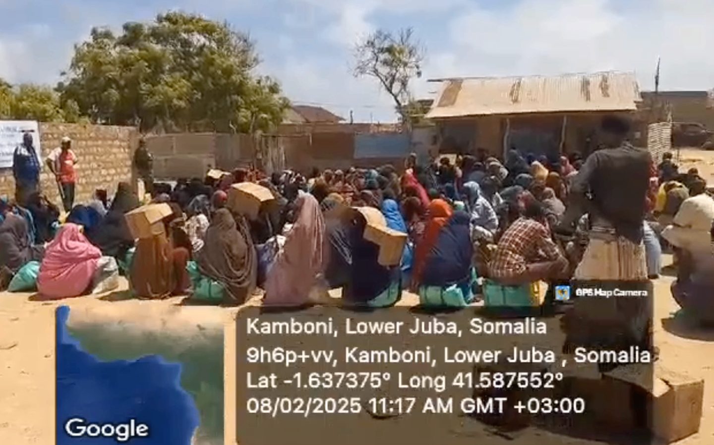 Families seated with relief supplies during a second JCC food distribution in Ras Kambooni