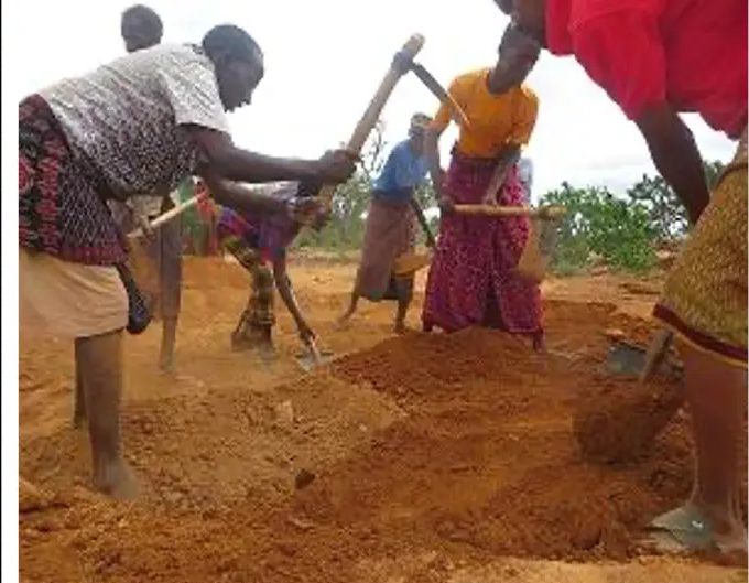 Women digging in close formation on the edge of a catchment basin